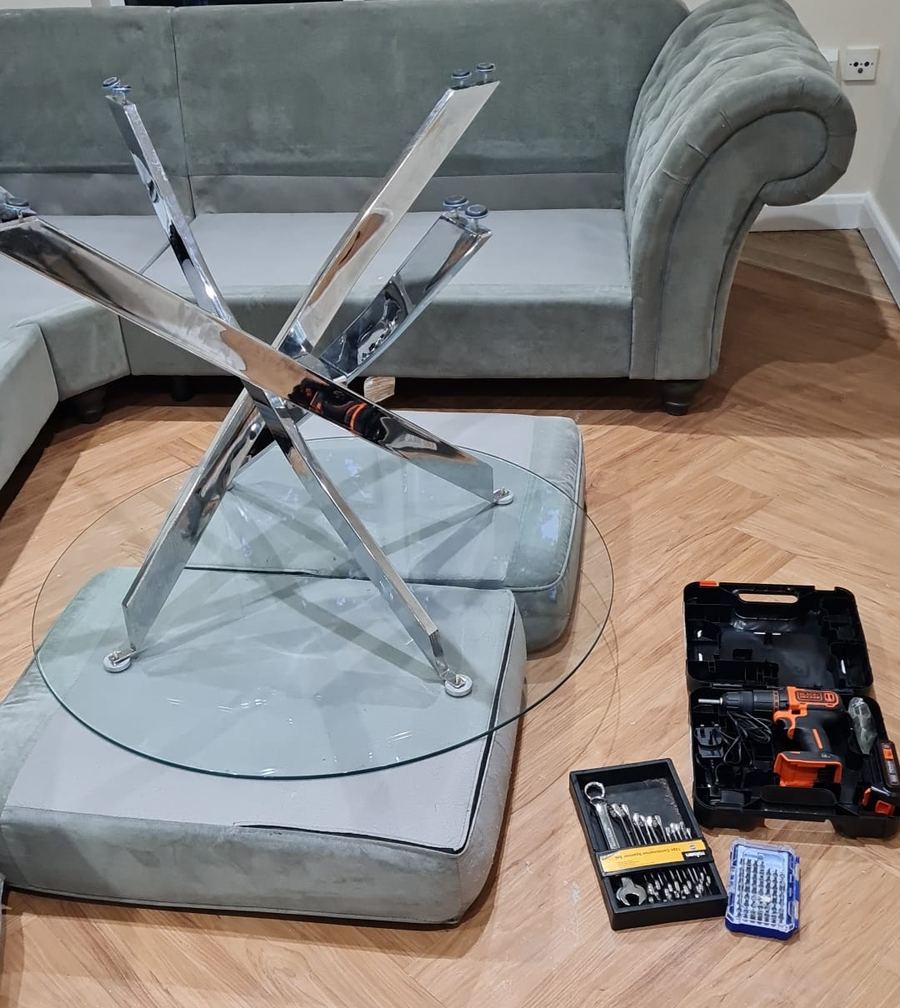 Glass dining table taken apart safely on soft cushions, tools ready